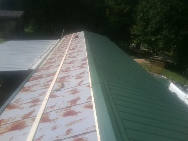 Old rusted panels beside newly installed green metal roofing — Wind Damage Roof Repair by Roofing Brothers in North Ridgeville
