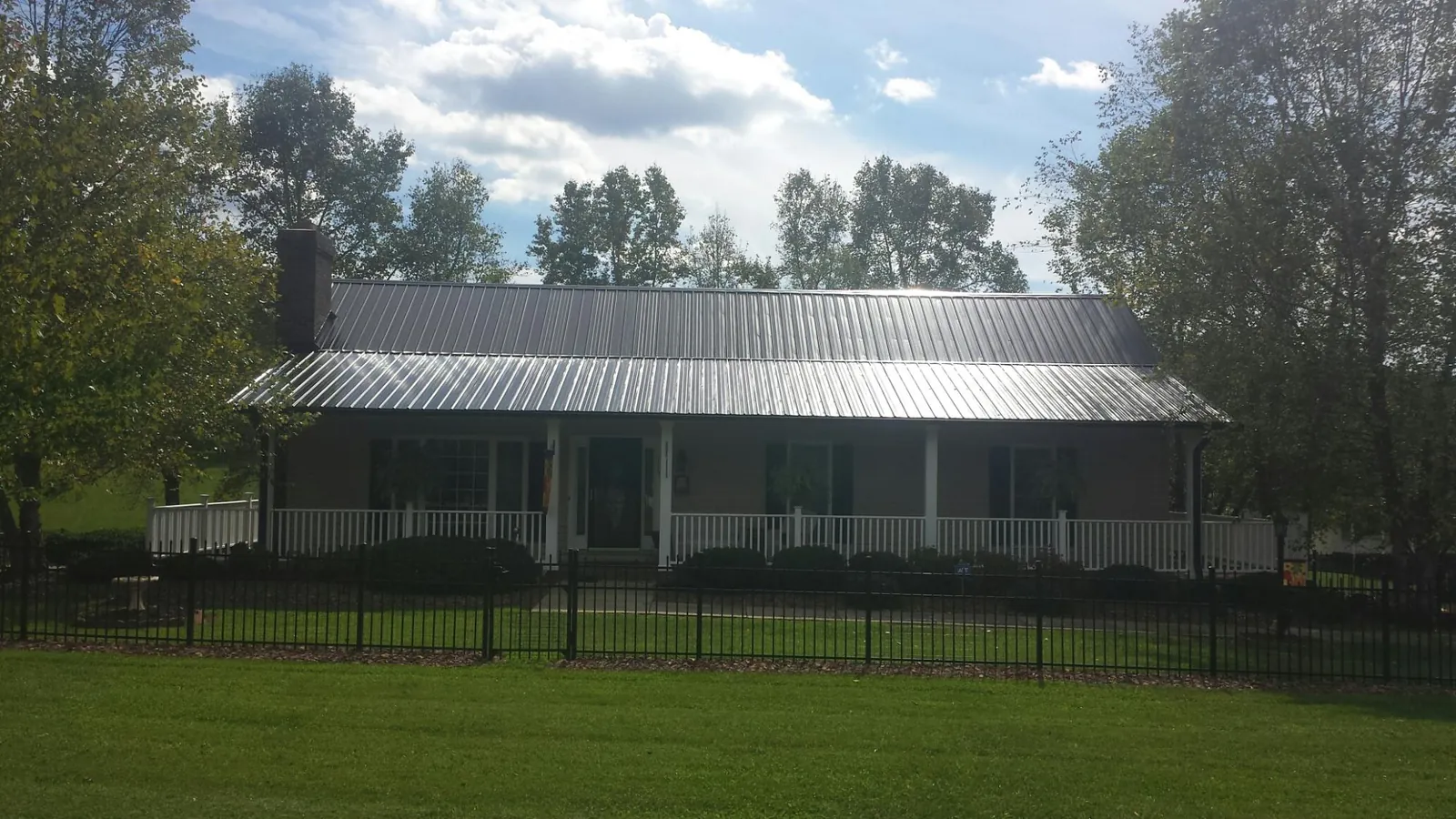 Gray metal roof on a brick ranch with a full width front porch — Gutter Guard Installation work by our crew in North Ridgeville