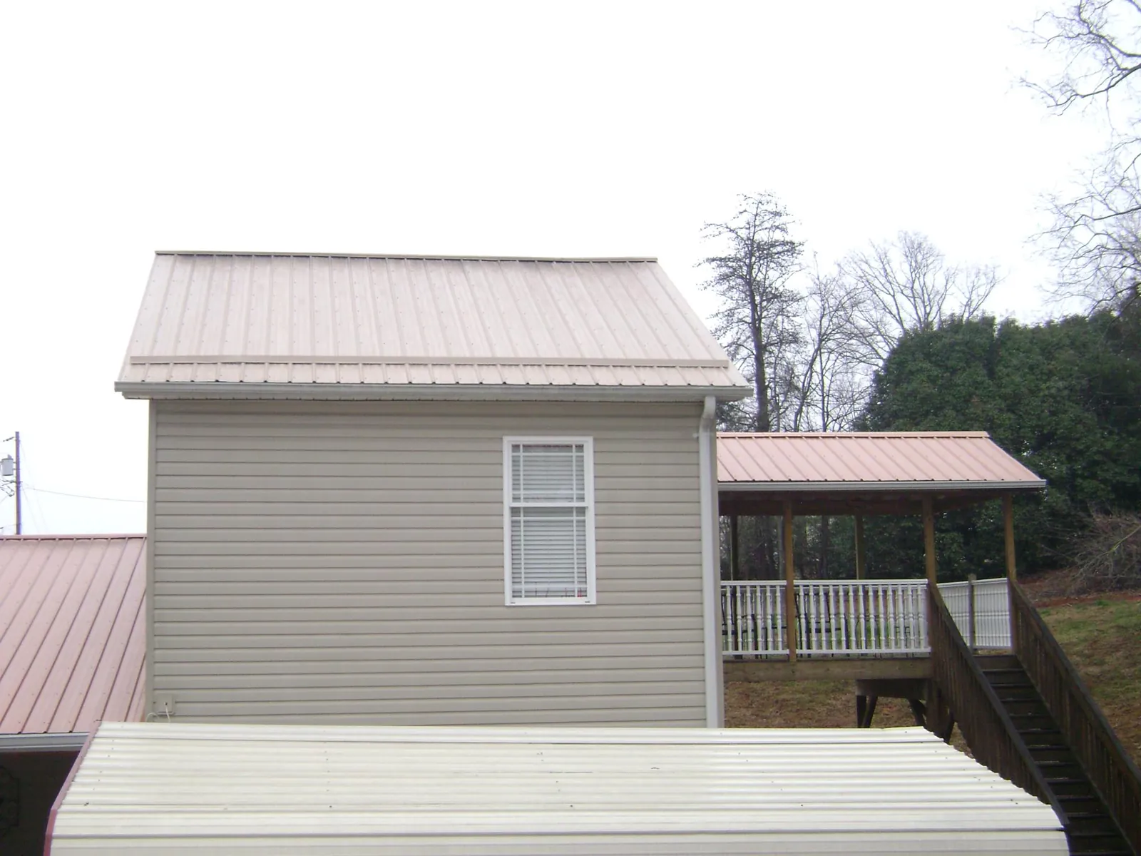 Tan metal roofs on a two story addition and attached porch, from a Roof Replacement job in North Ridgeville