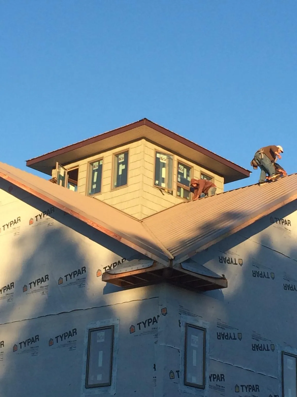 Roofers working around a rooftop cupola on a new metal roof at sunset — Roof Waterproofing in North Ridgeville by Roofing Brothers